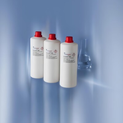 Drei weiße Reagenzienflaschen aus Plastik, jede mit einem roten Schraubverschluss versehen, sind in einer Reihe angeordnet.
